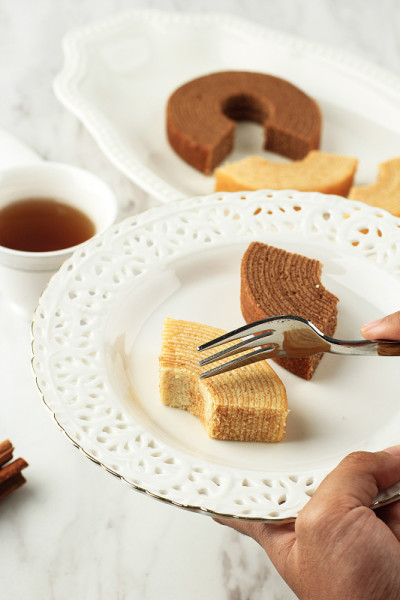 女手洞板与一片Baumkuchen或树蛋糕(木头蛋糕)是一种从德国美食吐蛋糕。它也是日本很受欢迎的甜