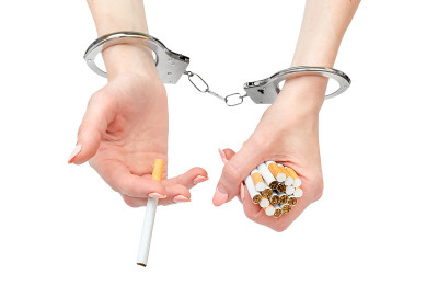 手戴手铐，白色背景上有香烟。吸烟的习惯。