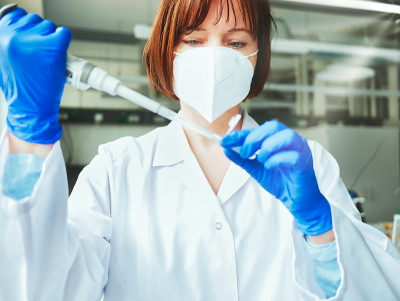 科学家或实验室研究人员戴着防护面罩和实验室手套，手持实验室吸管，将样本移液管入试管。医学诊断、研究和