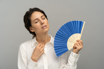 疲惫过热的女员工解开上衣最上面的扣子，用扇子热出汗