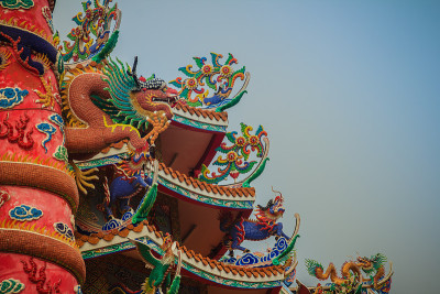 五颜六色的中国龙绕红柱雕像。在中国公共寺庙中，寺庙柱周围雕刻着美丽的龙像。