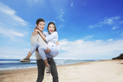 幸福的亚洲夫妇在海滩上微笑