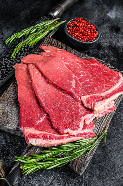 生的新鲜牛肉圆牛排配香草和香料。黑色背景。俯视图