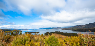 在前景中有云朵、明亮的蓝天和天然灌木植被的沿海荒野地区的视图。