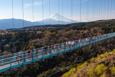 人们走在三岛天桥上，看到远处的富士山，晴朗的日子