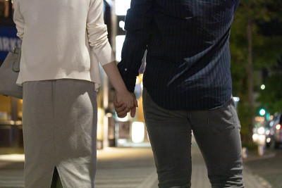 男人和女人手牵着手在市中心晚上的后视图