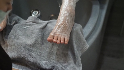 脚Spa。在水疗店的肥皂水机里，女人光脚按摩。女人的脚进入脚浴在热水手持式。在水疗沙龙用脚油按摩。放