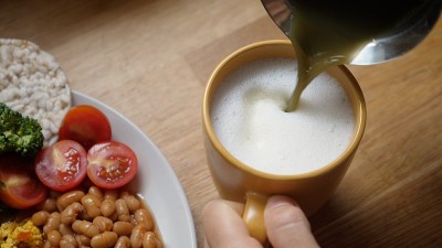 把抹茶倒进植物奶泡的俯视图。健康的素食早餐