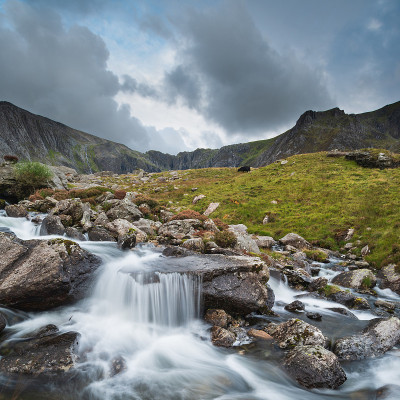 秋天，在斯诺登尼亚的Llyn Ogwen和Llyn Idwal附近，一条河流顺着山脉流下的穆迪景观图