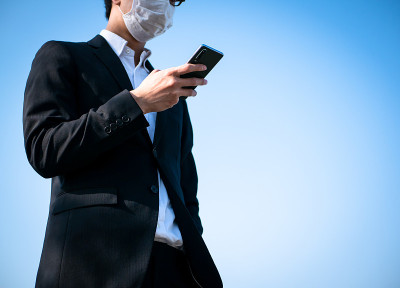 一名戴着面具的商人正在操作智能手机
