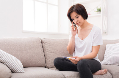 沮丧的女孩拿着验孕棒打电话