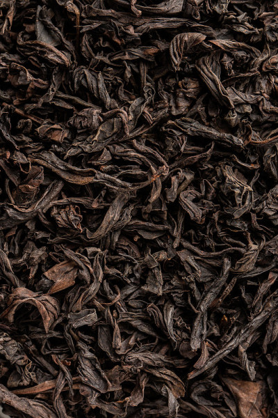 一堆干茶叶。干红茶。有纹理的背景是芳香的红茶干叶子和肉桂