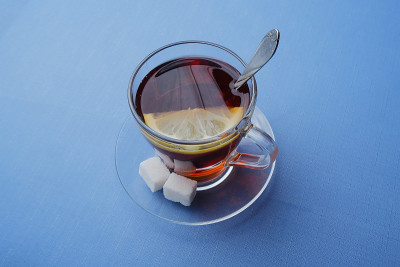 蓝色背景的玻璃碟子上放着一杯柠檬茶和两块糖