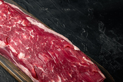 新鲜生牛肉。整块里脊肉与牛排，在黑色的石头背景，与文本复制空间
