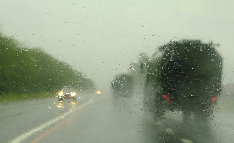 高速公路上的一列现代化军车。通过被雨覆盖的汽车挡风玻璃看到的散焦交通这是在秋天