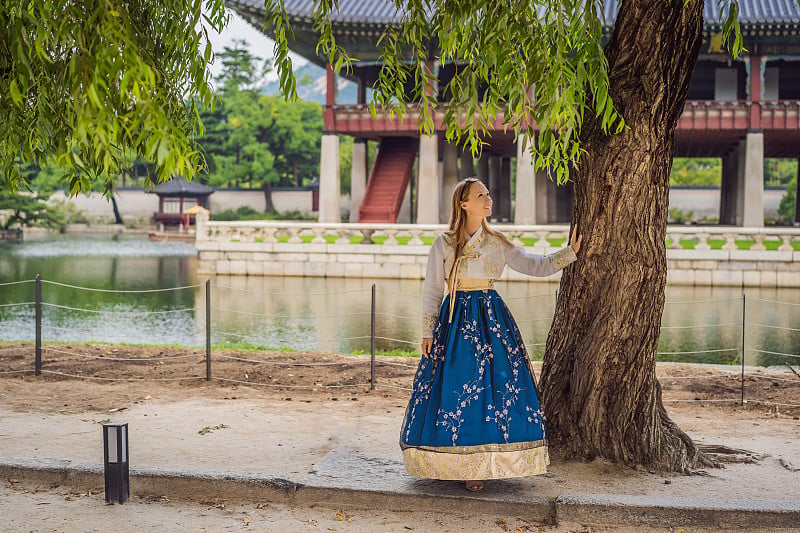 身穿韩服的年轻白种女游客在韩国宫殿。韩国旅游概念。国家韩国的服装。为游客提供的娱乐——试穿韩国民族服