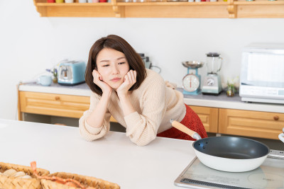 漂亮的亚洲女人在厨房做饭，担心