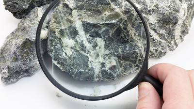 手用放大镜检查石头中的石棉纤维