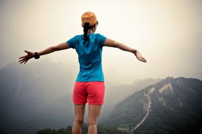 自由女徒步者在山顶向长城张开双臂