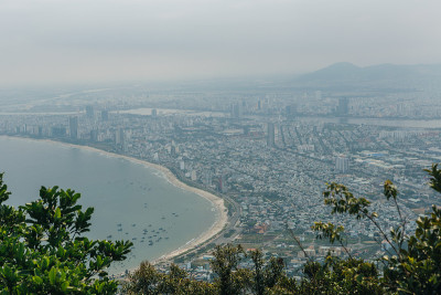 越南岘港海凡山口顺化的琅哥海滩全景。火车在海边的铁路上行驶，绿色的森林，美丽的自然景观，海浪