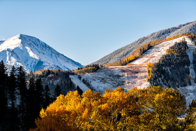 阿斯彭，科罗拉多州著名的酪乳或高地滑雪坡山顶在岩石山在阳光明媚的日子与黄色树叶上的雪秋天的树木