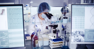 研究DNA突变的多种族女性团队。在防护服中使用显微镜