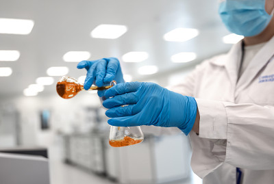 烧瓶与棕色液体在科学家手中与化学液体滴试管，科学和医学研究和发展的概念