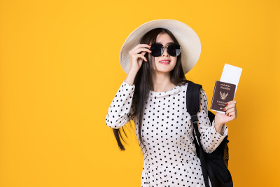 夏日休闲装的女游客。亚洲微笑女子。以黄色为背景出国旅行的乘客。一个亚洲女人要去度暑假。旅行有趣的旅行