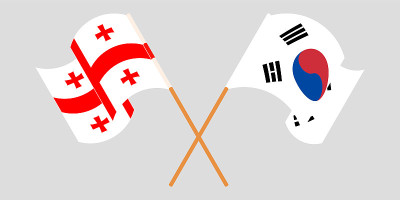 Crossed and waving flags of Georgia and South Kore