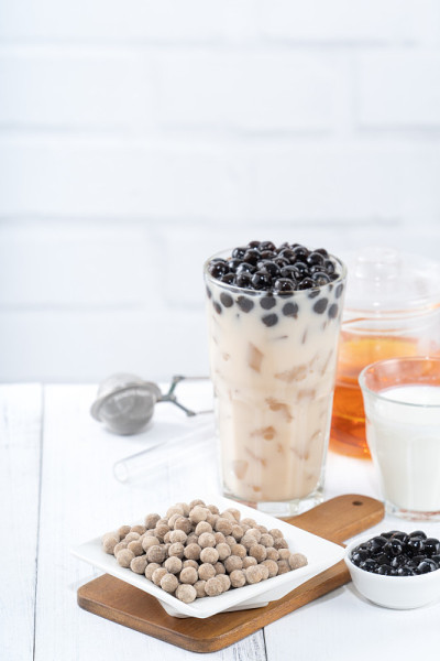 以珍珠为配料的珍珠奶茶，台湾著名饮品放在白色木桌背景的饮料杯上，近距离复制空间