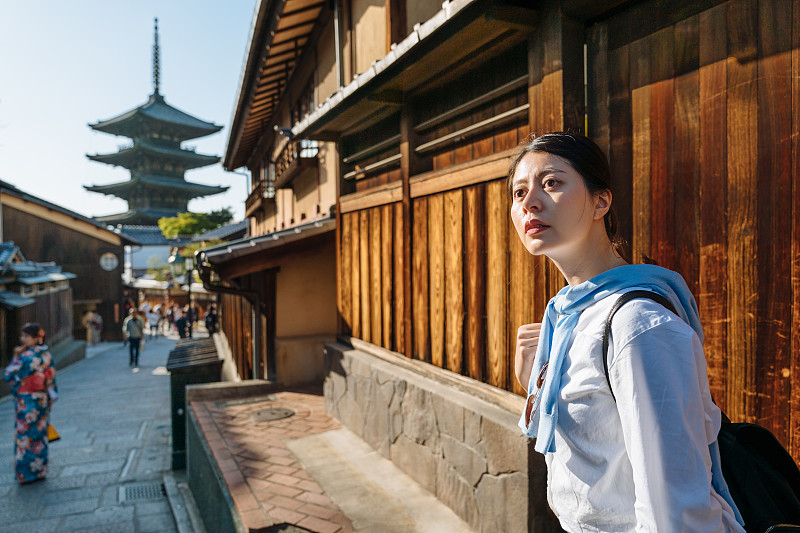 一个阳光明媚的日子，在日本京都旅行的亚洲女孩在Yasaka dori上凝视着远方。