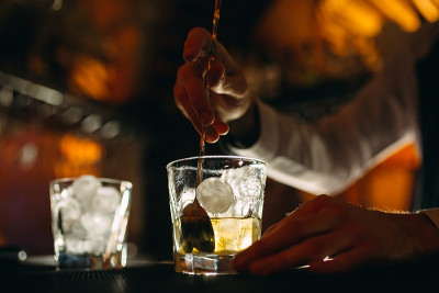 调酒师将一勺威士忌加冰倒入玻璃杯中搅拌。