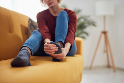 脚疼的女人坐在家里的沙发上。