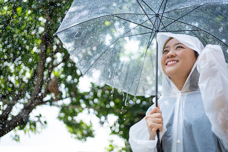 亚洲女性会撑伞、穿雨衣。