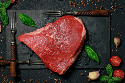 生牛排放在石头砧板和叉子上。用香料和药草喂养的肉。食物平躺