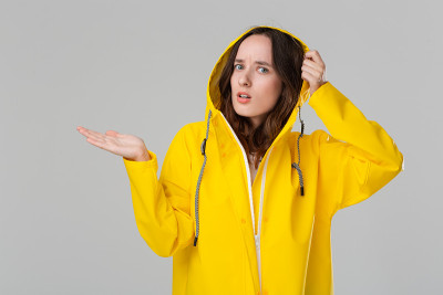 漂亮的黑发女孩穿着黄色雨衣检查是否下雨了。准备好迎接坏天气吧。