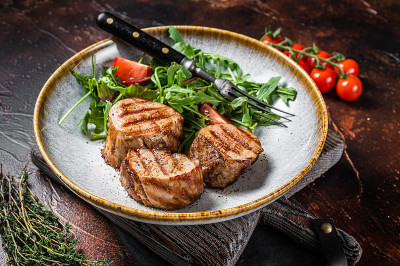 烤猪肉圆片牛排，里脊肉配沙拉。黑暗的背景。俯视图