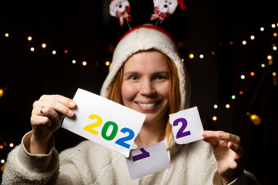 一位女士在黑暗中戴着新年帽，微笑着把2021年改为2022年。