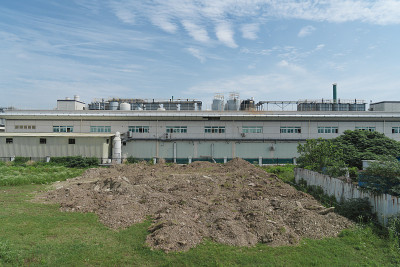 厂房位于市郊，以工业厂房为背景