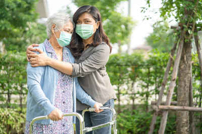 亚洲老年人或老年妇女走路时戴着口罩，以保护安全感染Covid-19冠状病毒。