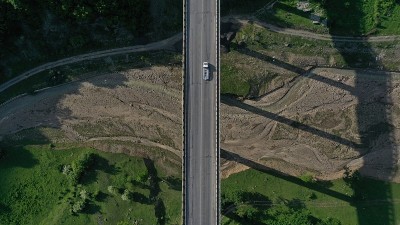 从空中俯瞰阿纳努里要塞和教堂附近的阿拉格维河上的桥。山的风景。夏天。绿色的树木。汽车在桥路上行驶。格