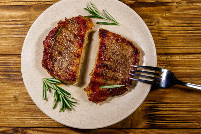 烤猪肉牛排与迷迭香在木桌上。俯视图