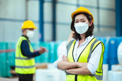 总工业工程师视察口罩厂。在使用笔记本电脑的时候画一个女人的肖像。他们表现出一种自信的态度。危险区域的