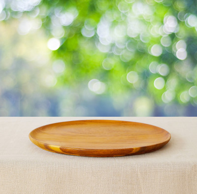 食物背景，空的木制盘子，托盘厨房产品展示在桌子上模糊的绿树自然花园与散景灯在夏季背景，木制盘子和公园