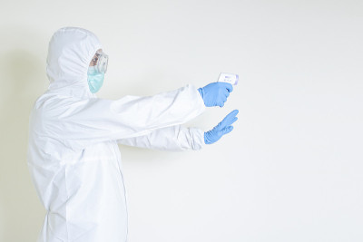男子穿着防护服，用平板红外体温计读取疫情传播传染性疾病新冠肺炎信息拷贝版面