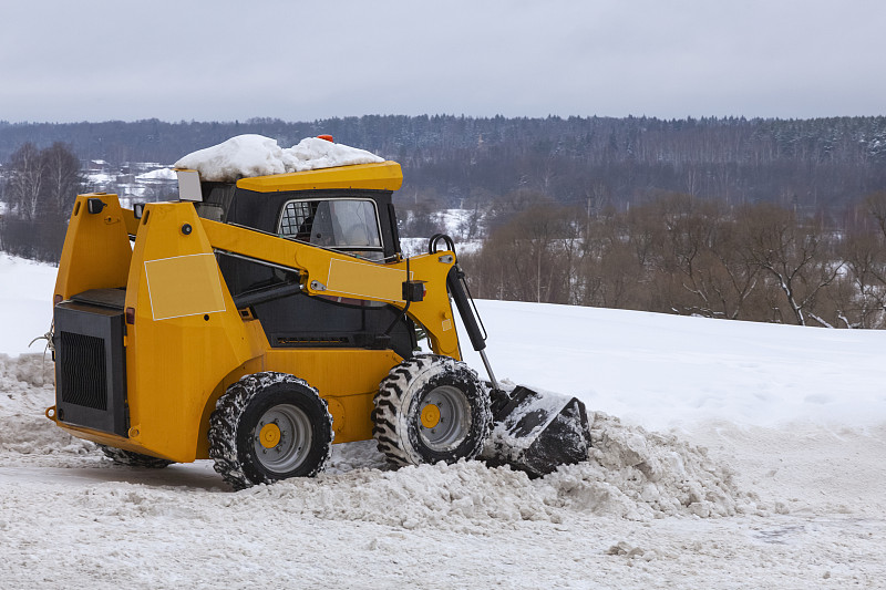 小型橙色铲车正在清理街道上的积雪