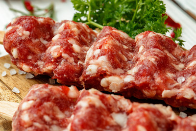 生的卢拉烤肉串，串上香料，放在木板上