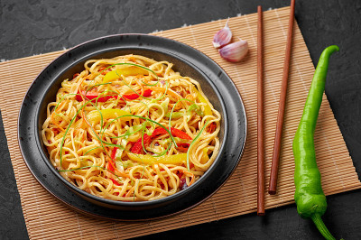 辣椒蒜味客家面在黑色的碗里，在黑色的石板桌上。印中素食菜肴。印度蔬菜面条。典型的亚洲餐