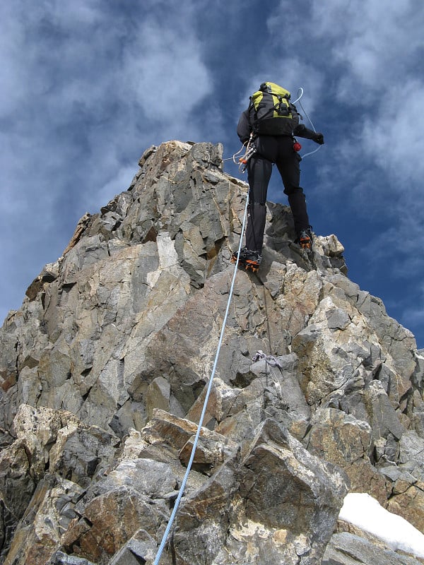 登山者从瑞士阿尔卑斯山脉的一座高峰上沿着陡峭狭窄的岩脊攀爬而下