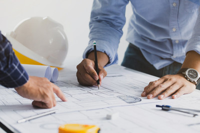 一个建筑项目的工程师会议。与合作伙伴和工程工具一起在建筑工地的办公桌上完成建筑项目的蓝图。